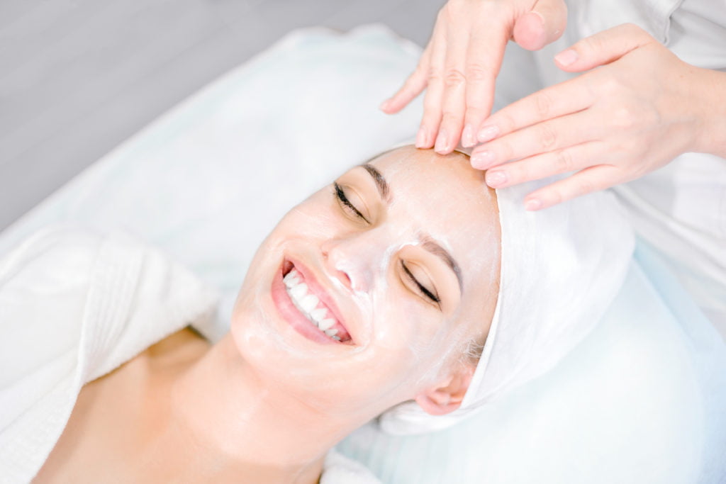 Beautician makes facial massage with mask. Beautiful smiling girl on spa procedure. Facial care | Mandalyn Academy in American Fork, UT