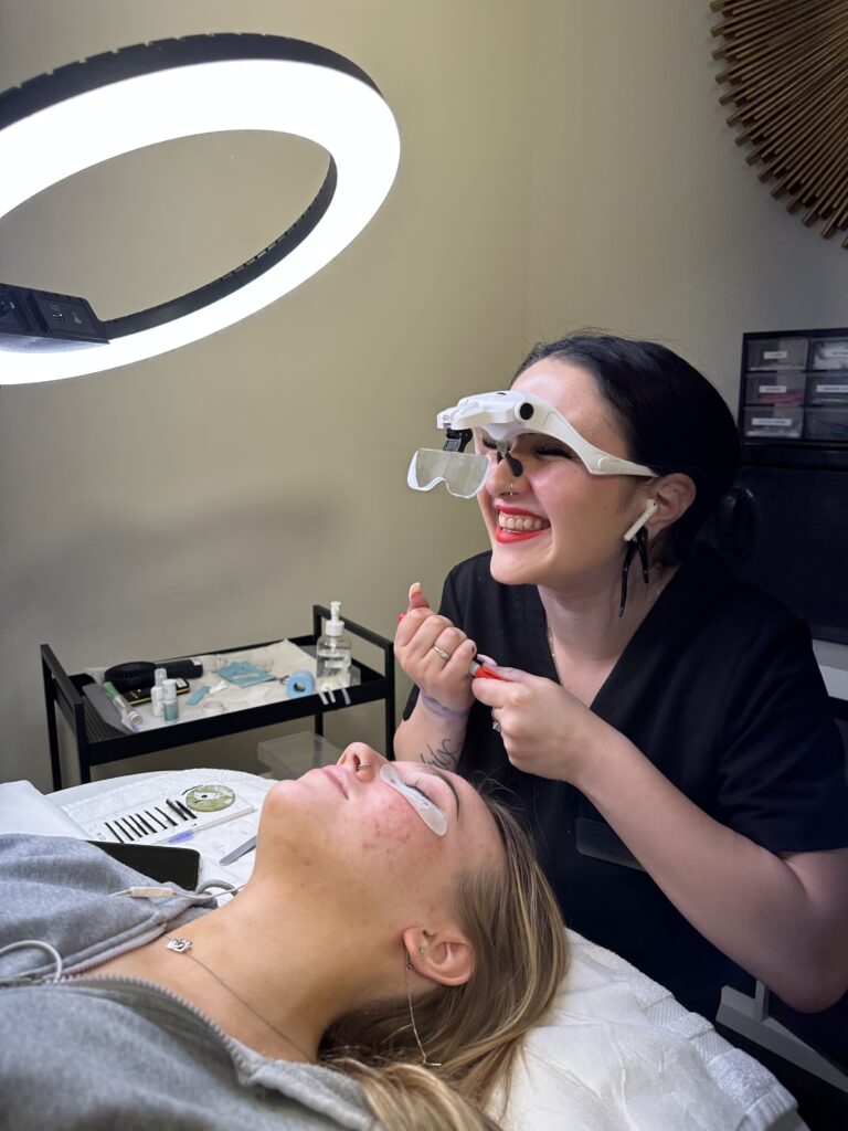 Nurse smiling with Eagle Magnifier Glasses doing Lash Extensions treatment to young woman | Mandalyn Academy in American Fork, UT