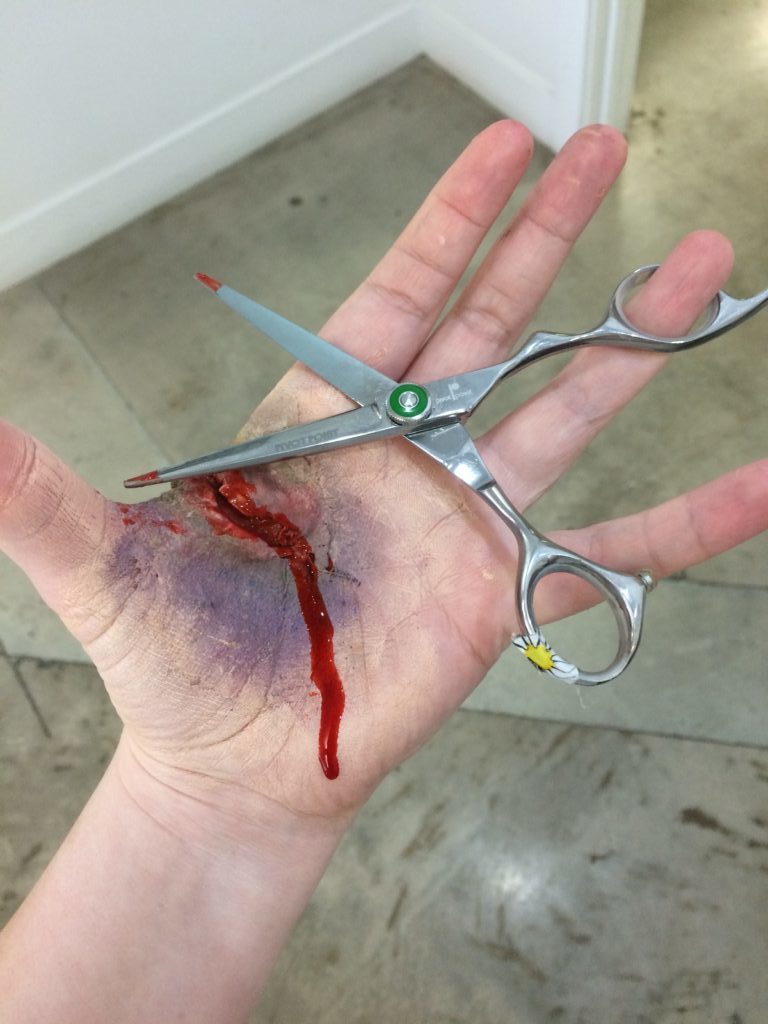 Woman holding a scissors and had a wound on her hand | Mandalyn Academy in American Fork UT