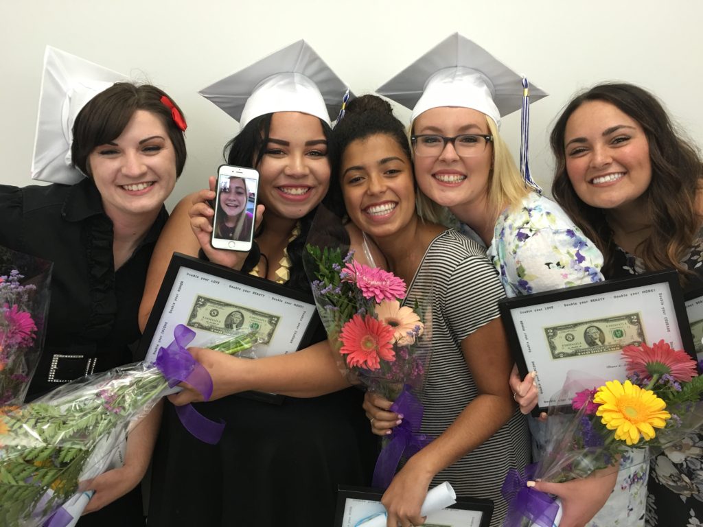 Group of women holding flowers bokeh with graduation hat | Mandalyn Academy in American Fork UT